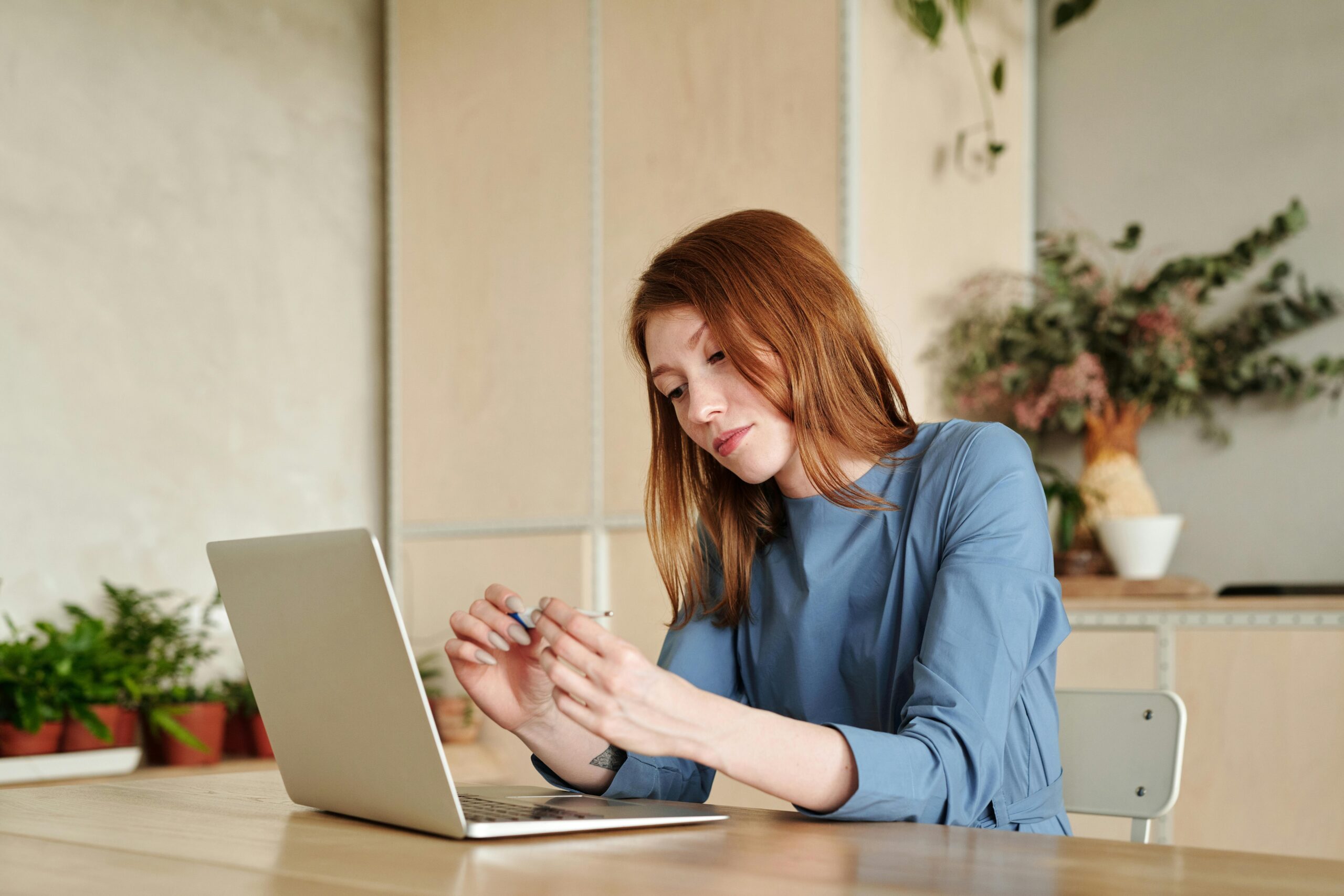 An image of a woman sitting in front of a laptop looking distracted representing a blog post on explaining that remote work is real work to family