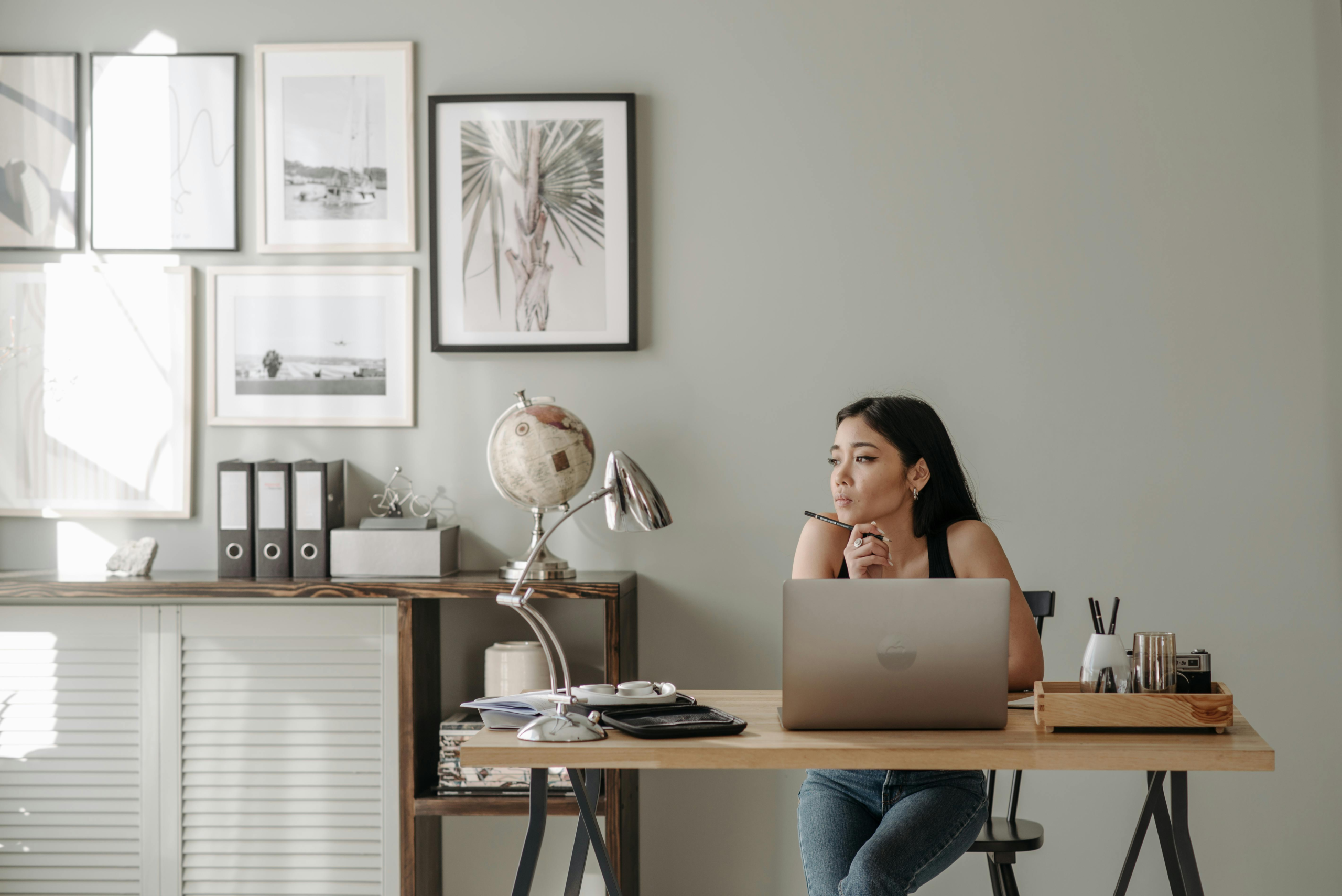 A picture of a woman working from home looking away from her laptop representing a blog post on how to stay focused when working from home