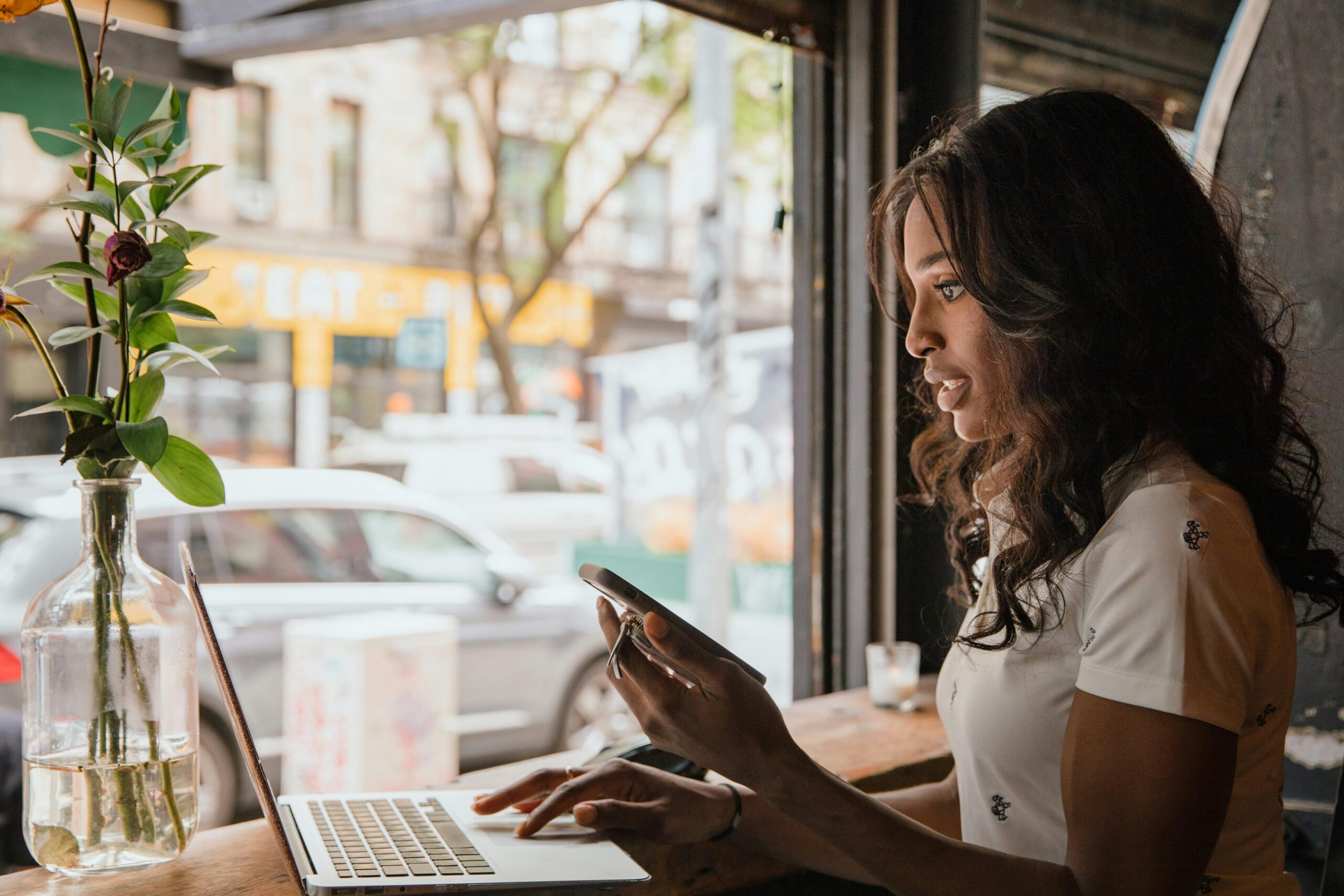 A picture of a woman working remotely at a coffee shop representing a blog post on places to work remotely other than home